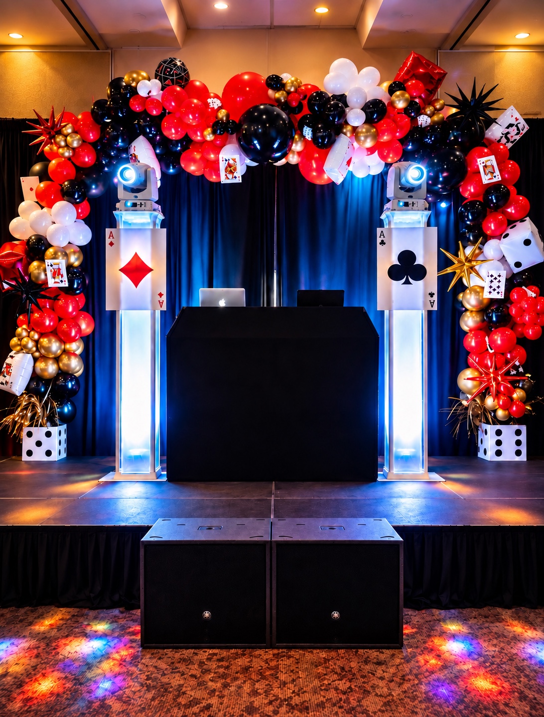 Casino-themed DJ setup with white lighting towers and red, black, white, and gold balloons