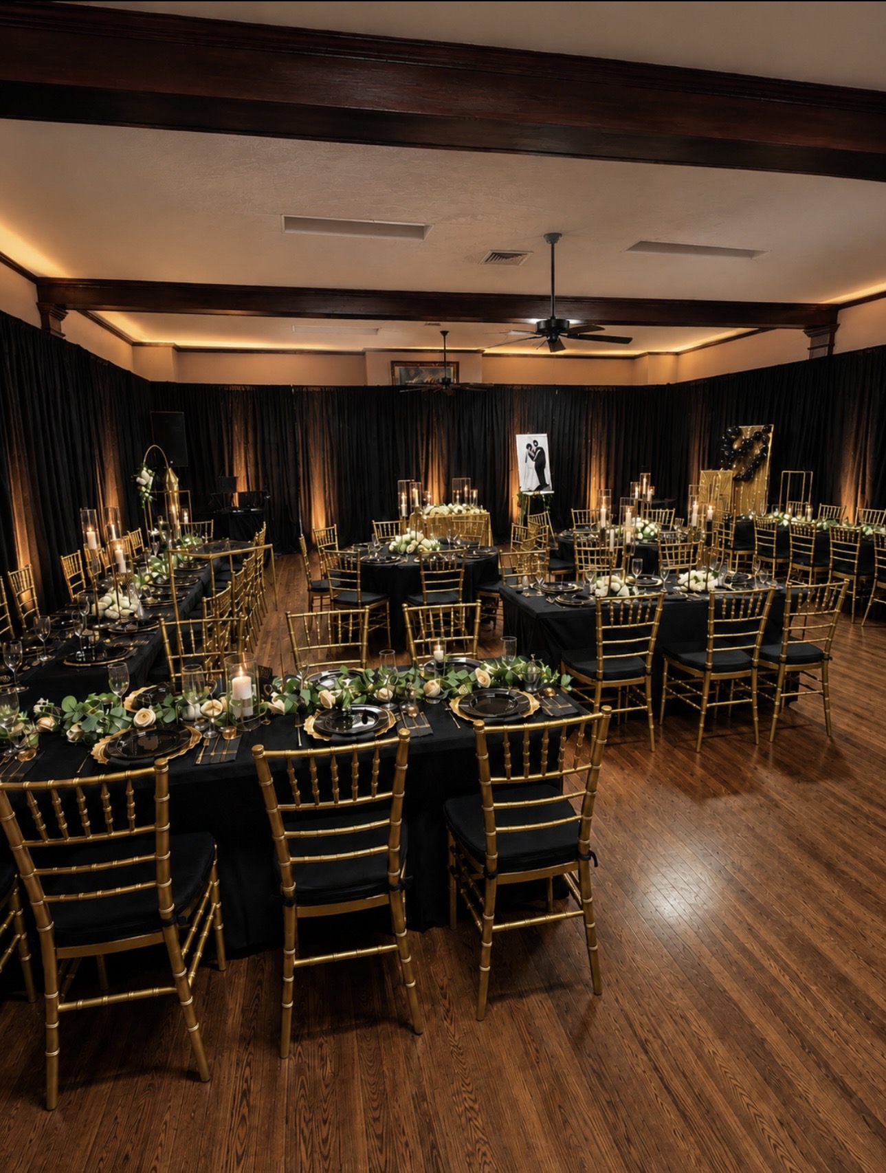 Black and gold reception with candlelit tables and warm uplighting